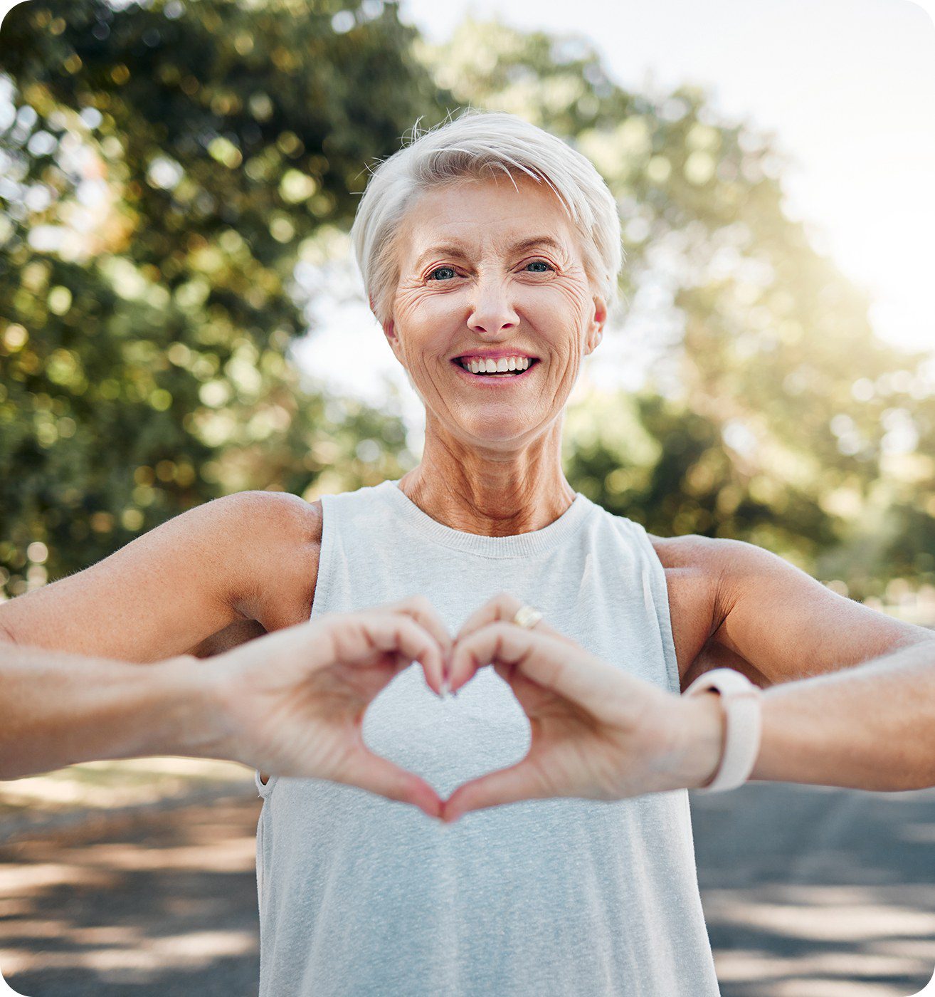 Smiling woman making heart shape with hands.