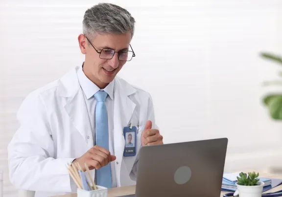 Doctor smiling while using a laptop.